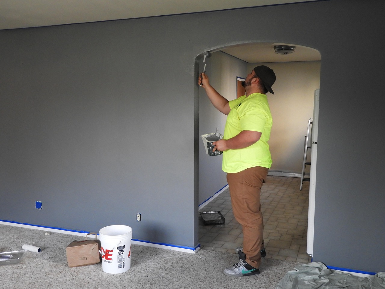 Painter rolling grey paint onto an interior wall